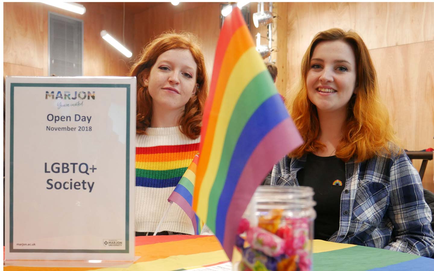 2 females behind LGBTQ sign