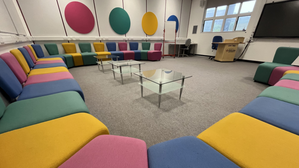 Brightly coloured chairs arranged around three small glass tables in Marjon's iSpace room