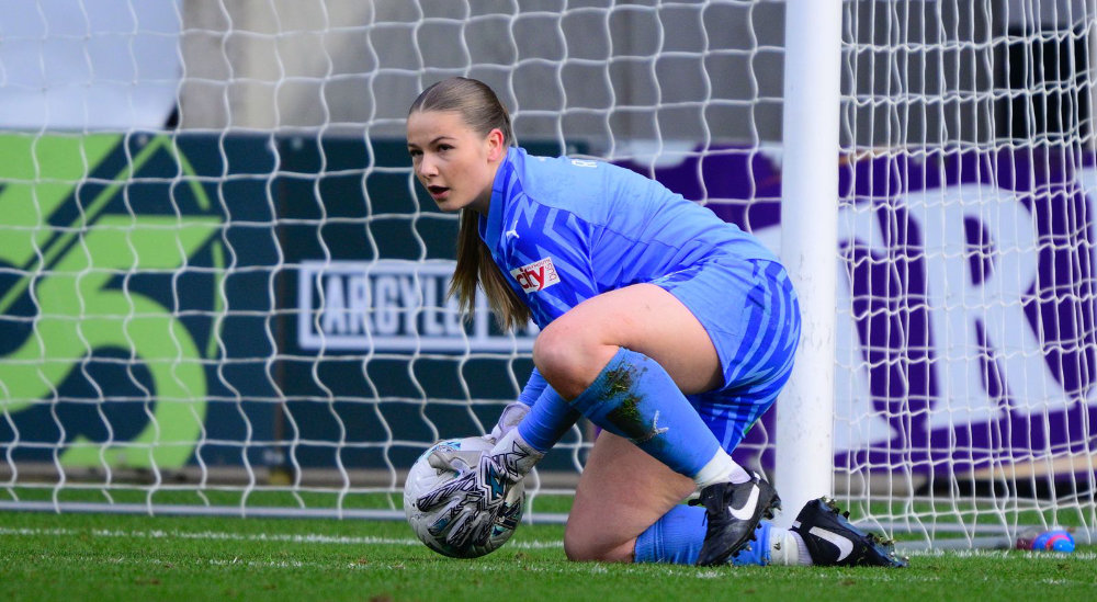 The Plymouth Argyle Women's team goalkeeper crouched in goal holding the ball