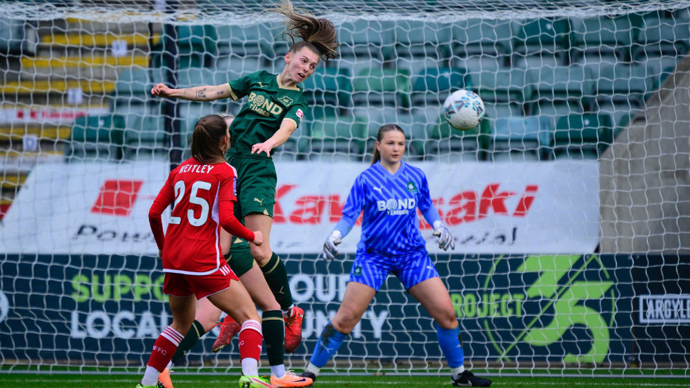 A Plymouth Argyle Women's team player heads the ball away from the Argyle goal