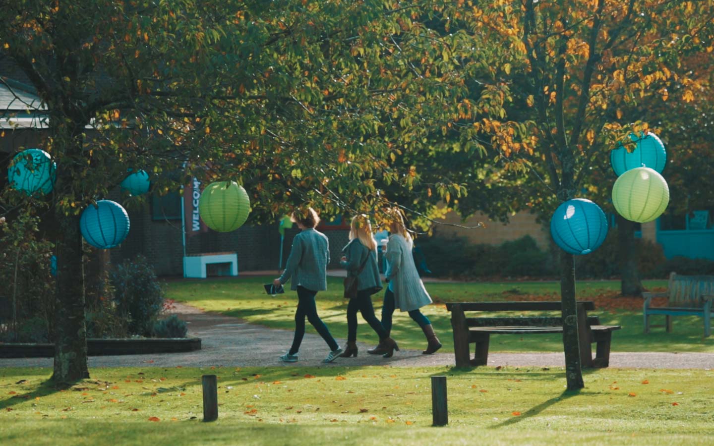 People walking on a the green campus with paper lanterns in the trees