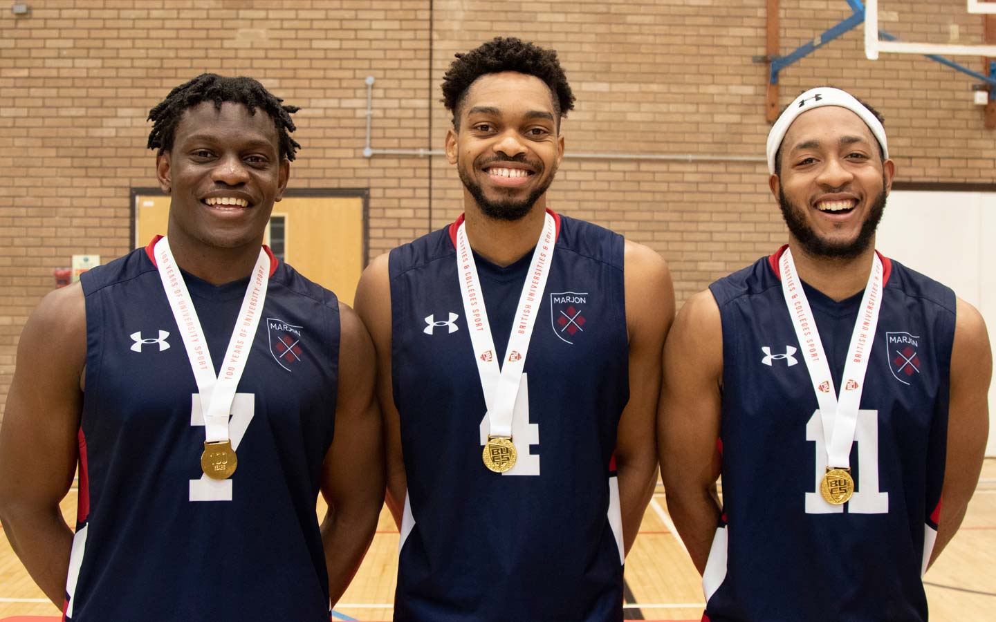 Three happy Marjon basketball players wearing medals