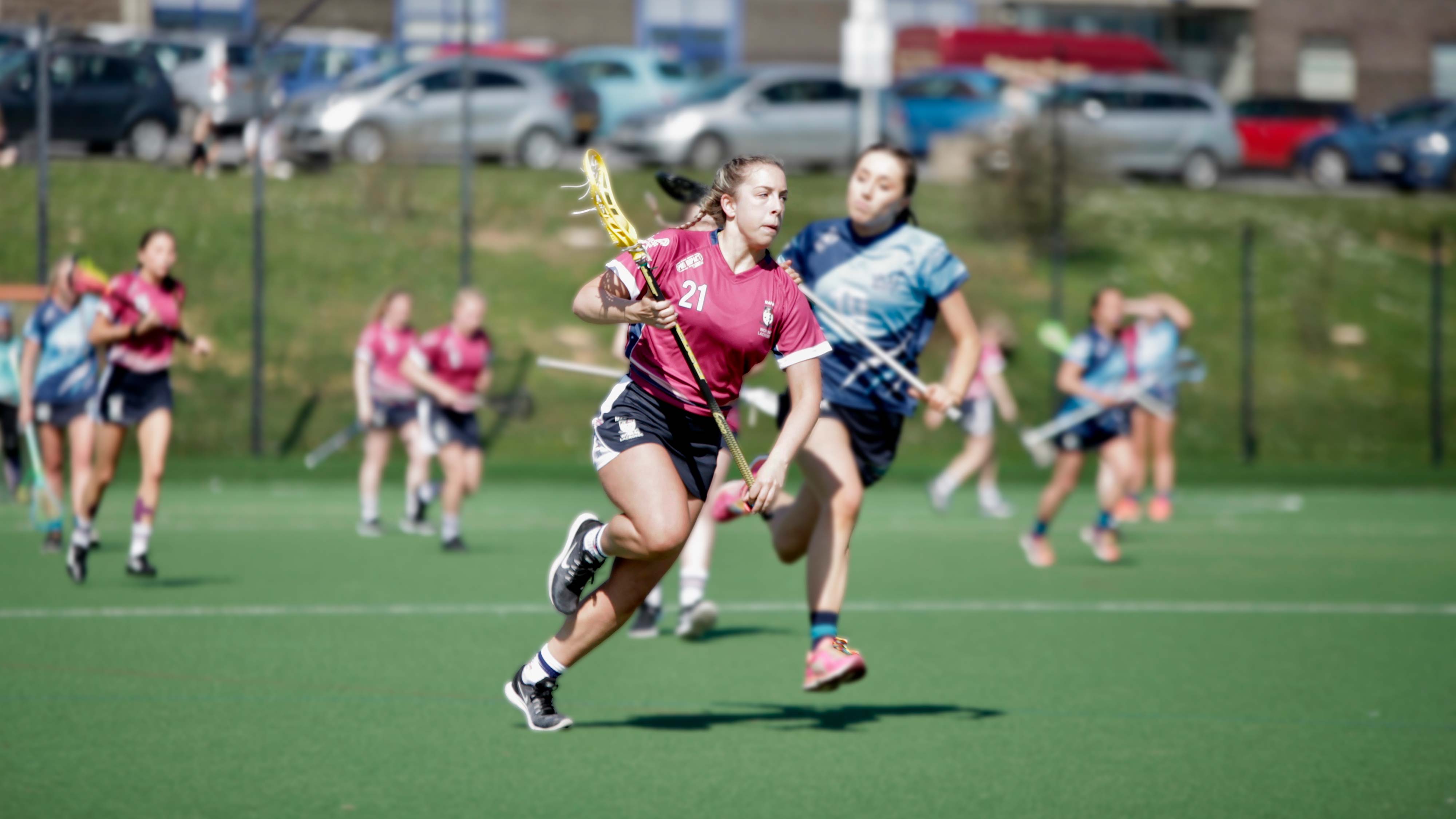 Two women running playing lacrosse 