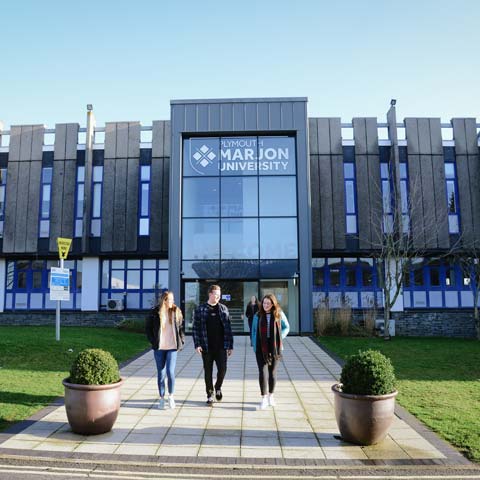 Three students walking out of the west entrance at Marjon