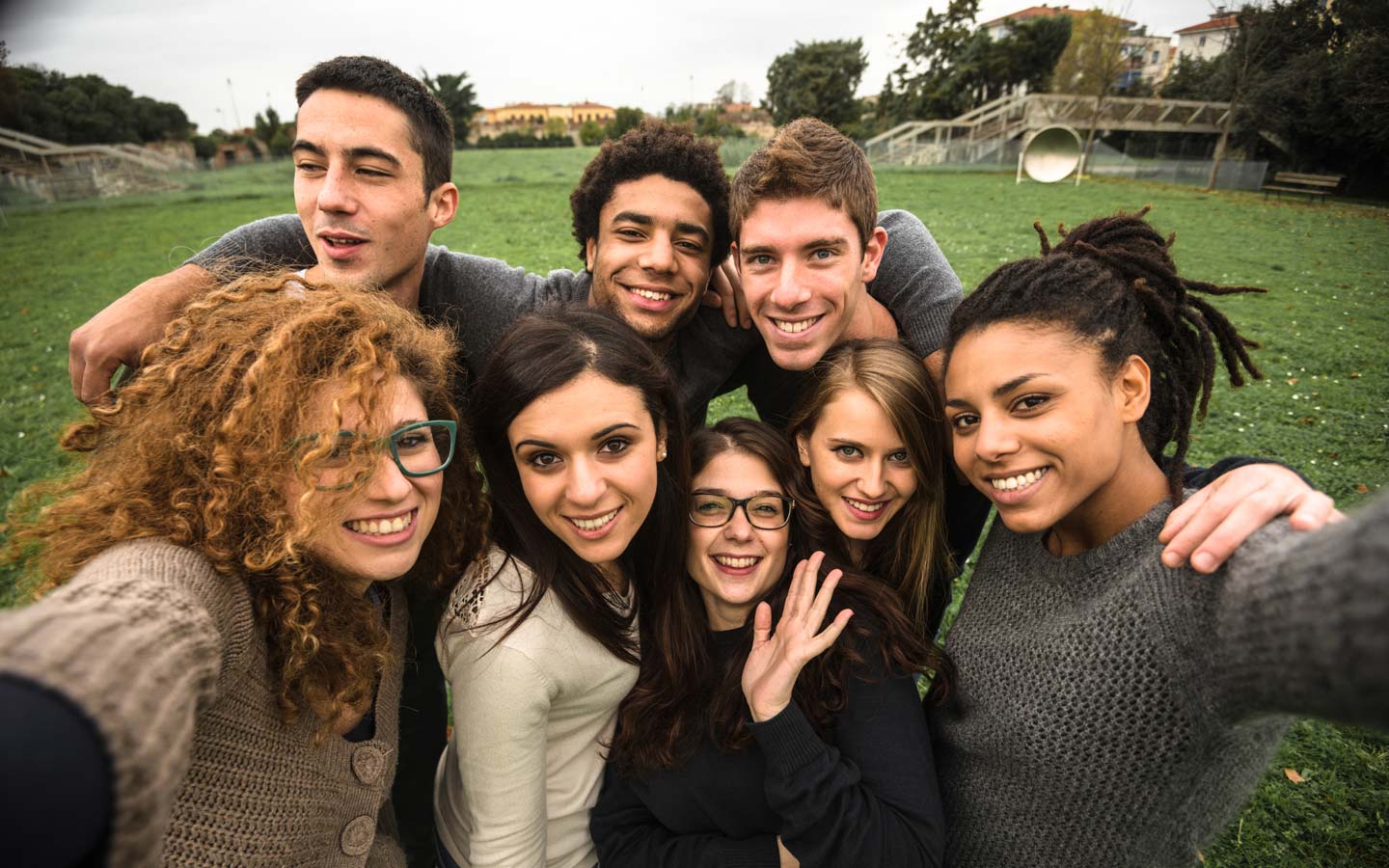 A large group of students with arms around each other smiling up at the camera