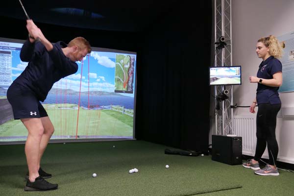 Two sport and exercise science students use the golf simulator