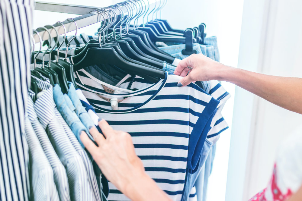 A person's hands rifling through a selection of clothing