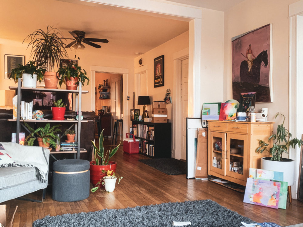 A living room with clutter and plants everywhere.