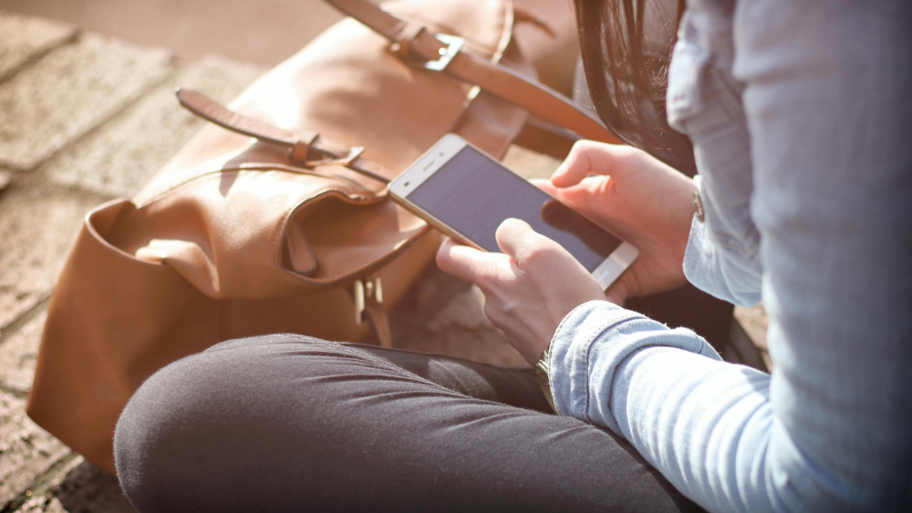 A woman's hands holding a mobile phone which she is typing onto.