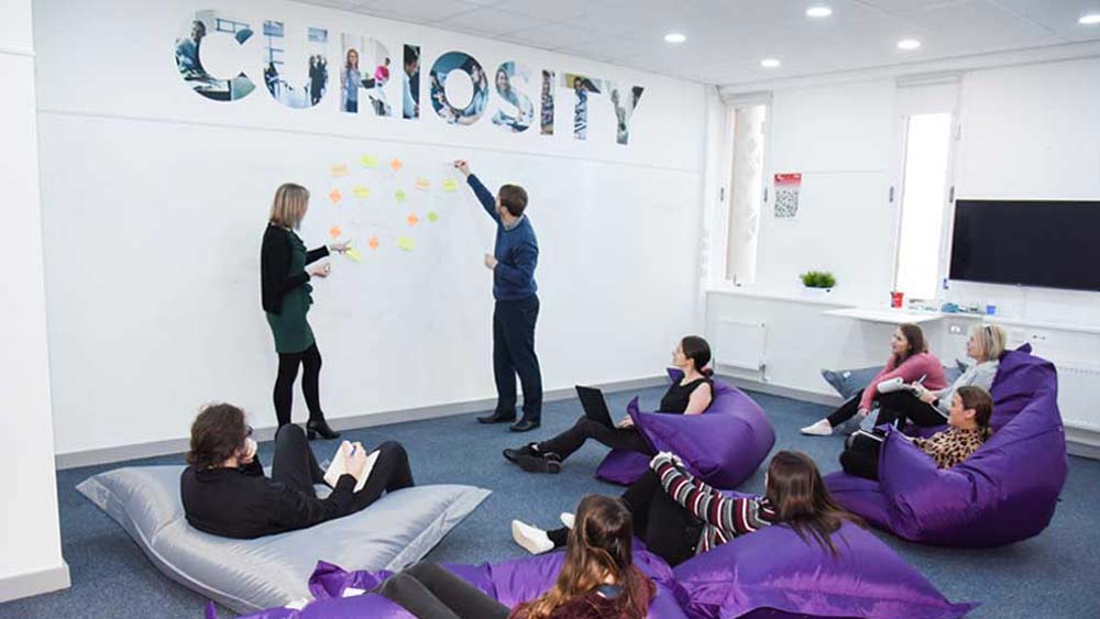 Students brainstorming ideas on the whiteboard wall in the Marjon Business School