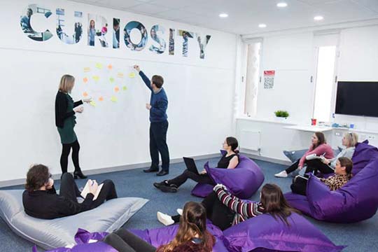 Students brainstorming ideas on the whiteboard wall in the Marjon Business School