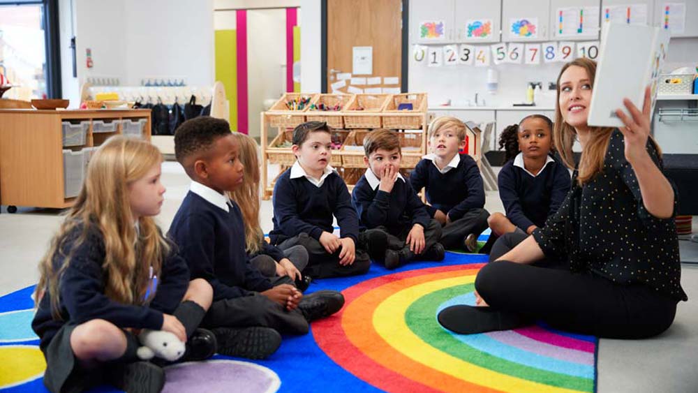 The class look om engaged as the teacher reads them a story