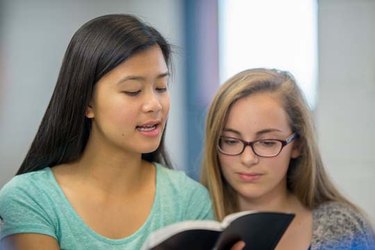 One pupil reads aloud as a second looks on