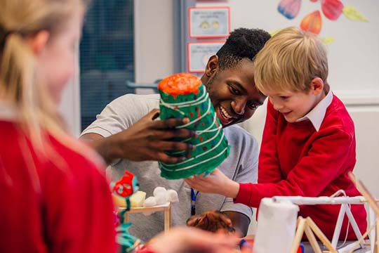 Teacher and pupil pick up a craft model for a closer look