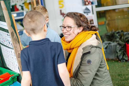 Primary teacher encourages Reception children in outdoors play