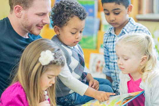 Early Years practitioner shares a book with young children