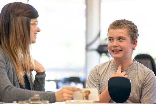 Speech and language therapist teaches vocal exercises to young client