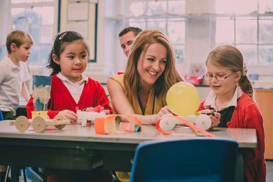 Teacher and two pupils do an activity with a balloon