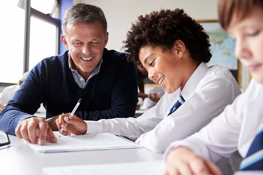 Maths teacher helps a pupil work through a sum