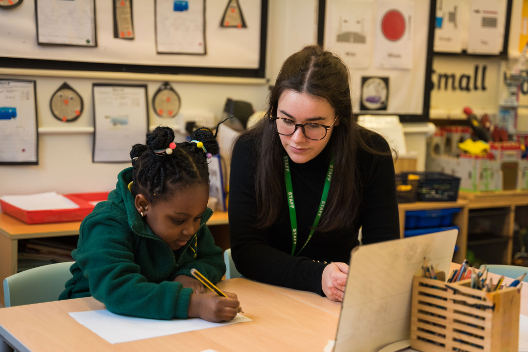 Marjon primary teaching student sitting with child in classroom