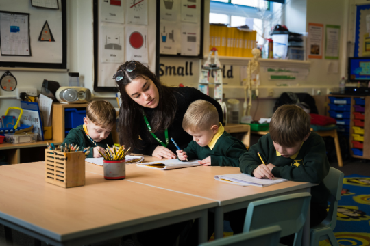 3 primary children, with Marjon student working at the table