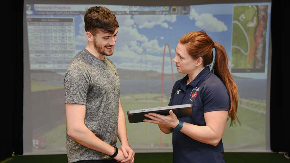 Two students track golf performance on the Trackman simulator in the biomechanics lab