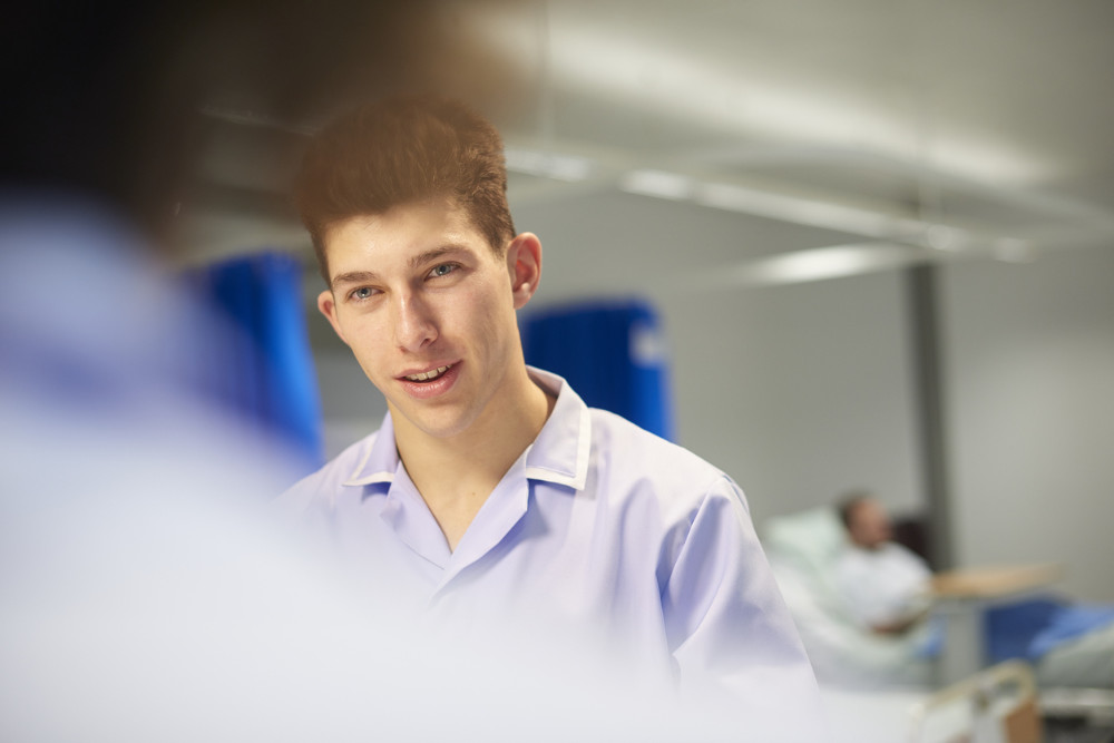 A man in a clinical setting wearing a blue shirt looks at a woman who is mostly obscured by the camera