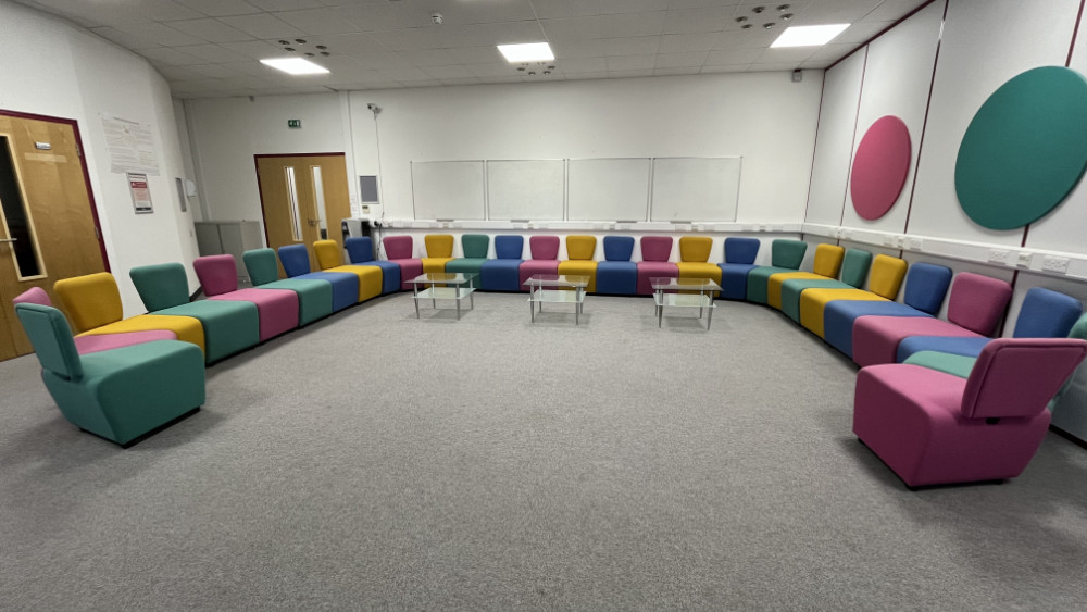A photo of Marjon's iSpace room, with chairs coloured pink, yellow, blue and green arranged in a half-circle