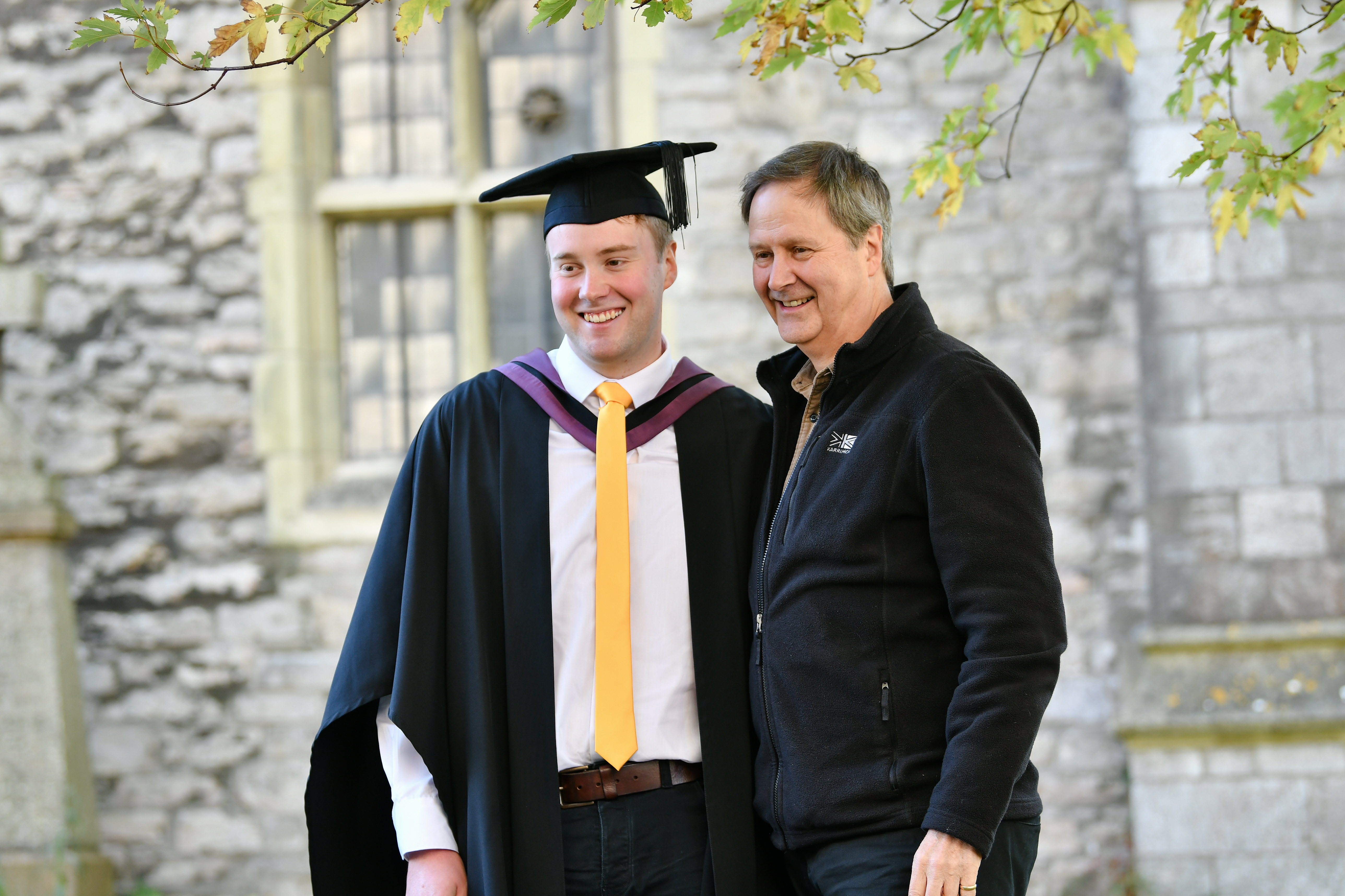 Graduate and his dad posing for a photo at graduation