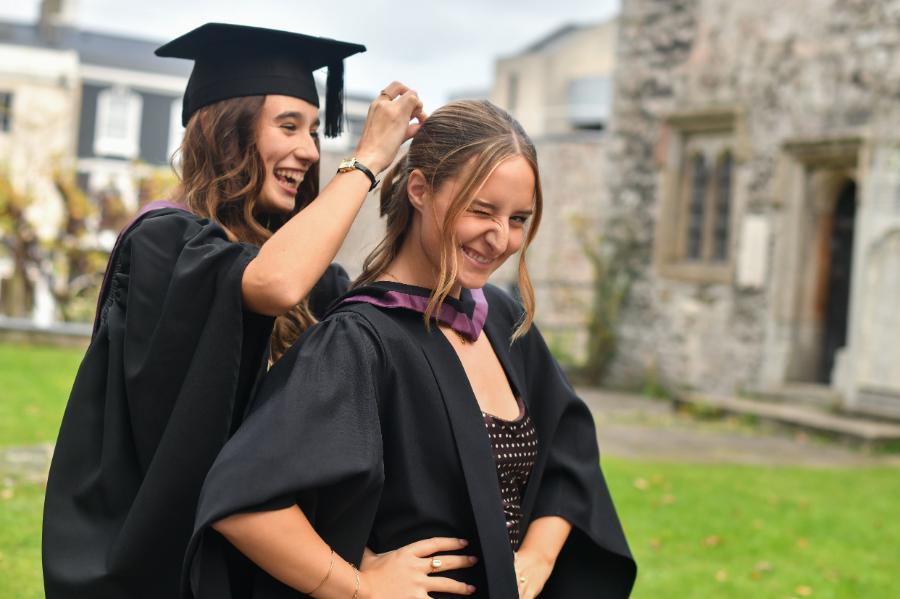 2 female students. One is helping the other with her hair.