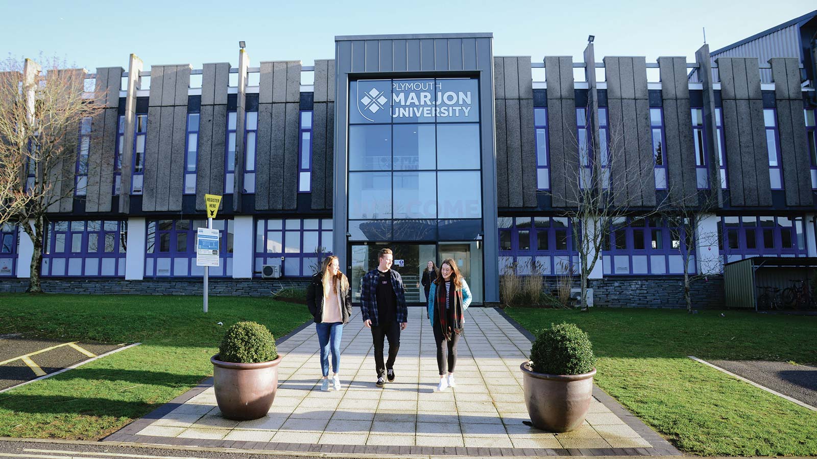 Three students walk out of the West Entrance on the Marjon campus