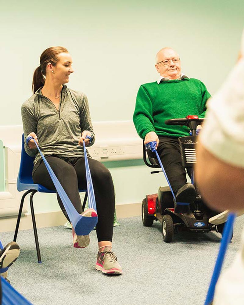 Student and elderly patient perform a stretching exercise with resistance bands