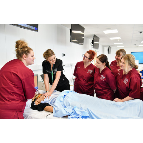 Students and a lecturer work with a simulated patient