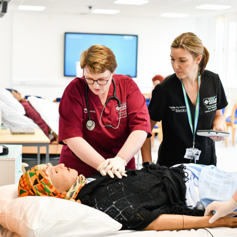 A lecturer and nursing student practising treatment on a simulation patient.