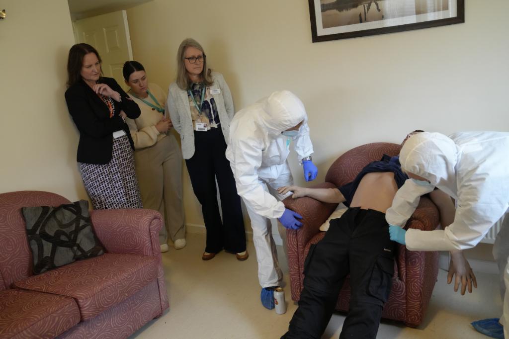 Alison Hernandez and Claire Taylor look on as students work with a mannequin in Marjon's own Crime Scene House.