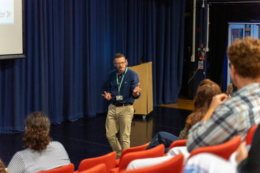 Male staff speaking to students in the quad theatre