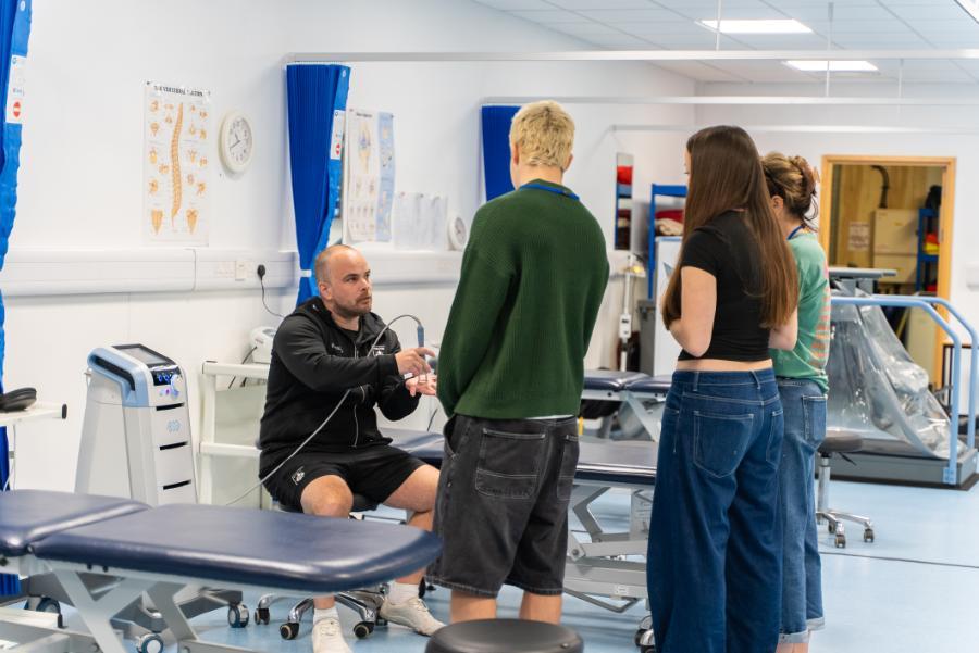 Male staff member, showing the equipment to 3 visitors on Open Day