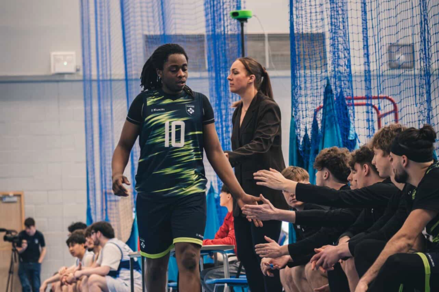 male basketball player returning to the bench getting high fives from teammates