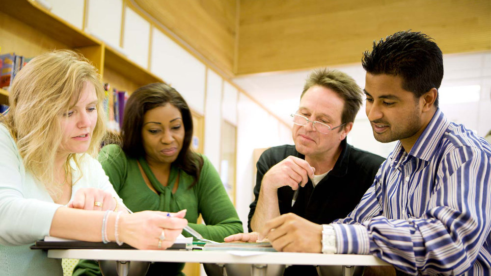 Diverse mature students at a library table working on some documents