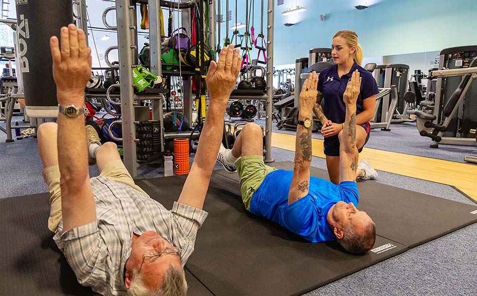 Student lifestyle co-ordinator teaches exercise to two older patients at the health clinic