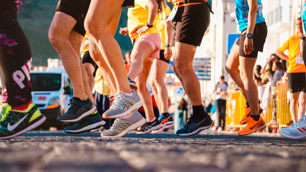 The feet of runners lined up on a street waiting to start