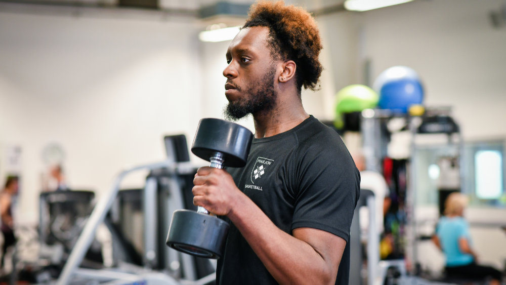 A man in a Marjon t-shirt lifting weights in our gym