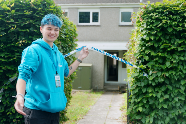 Student ambassador holding the police tape up outside of our forensic house