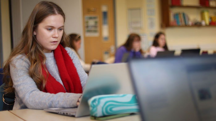 Student using laptop in classroom setting