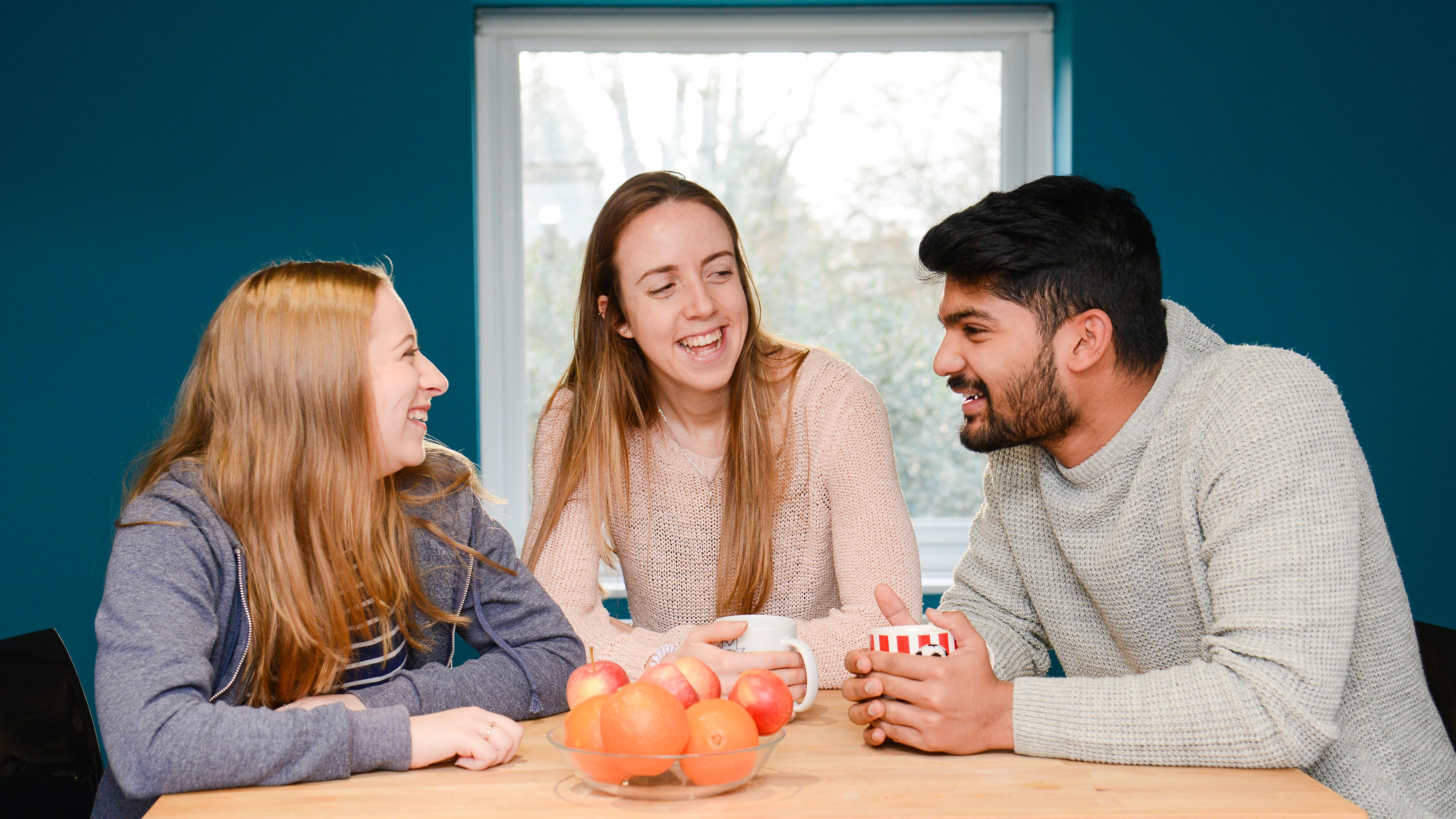 Three students sitting together in a village house
