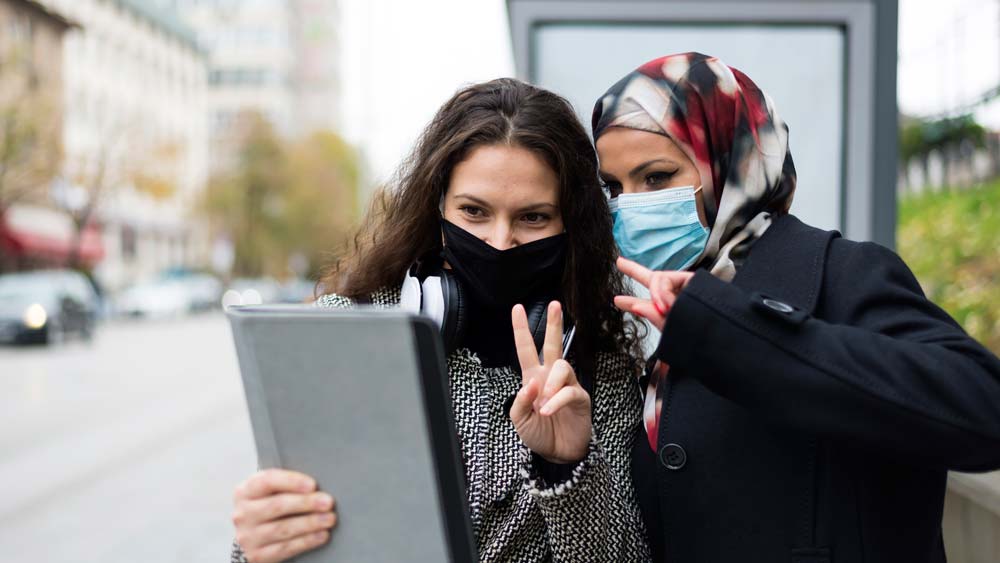 A woman and her international guest are taking a selfie in the street