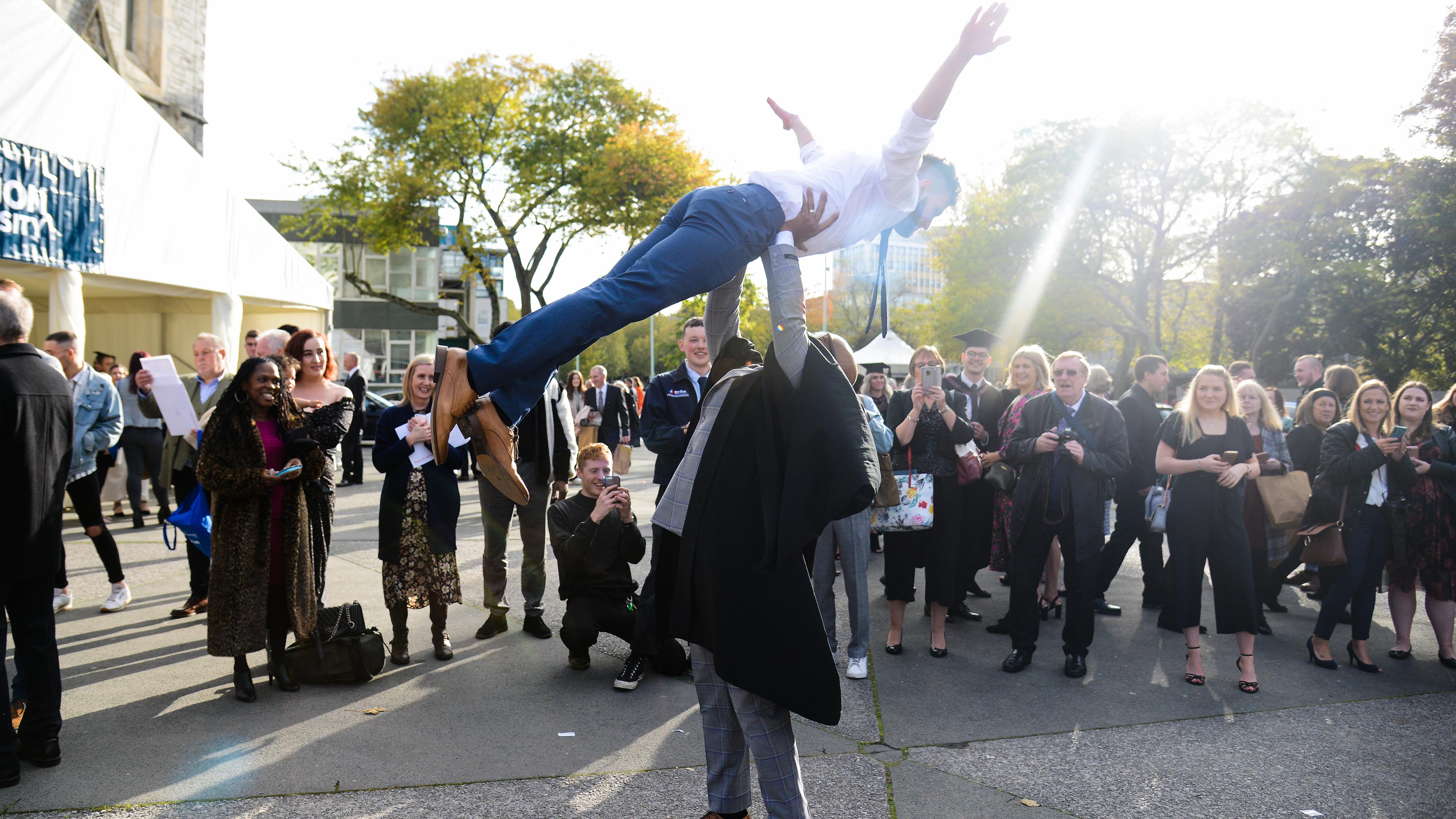 Graduate lifts up his friend in celebration