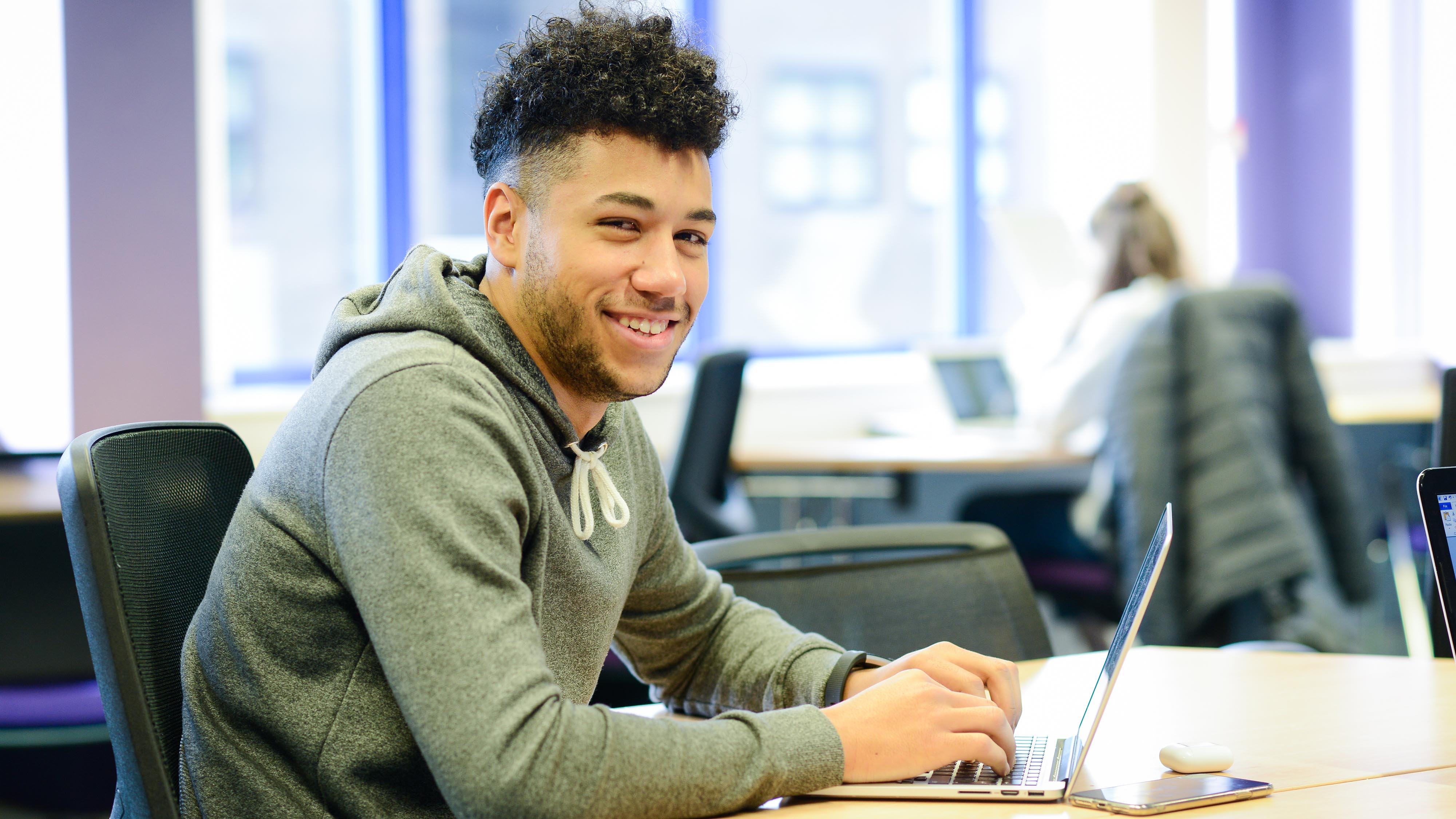 Student smiles at camera in the library