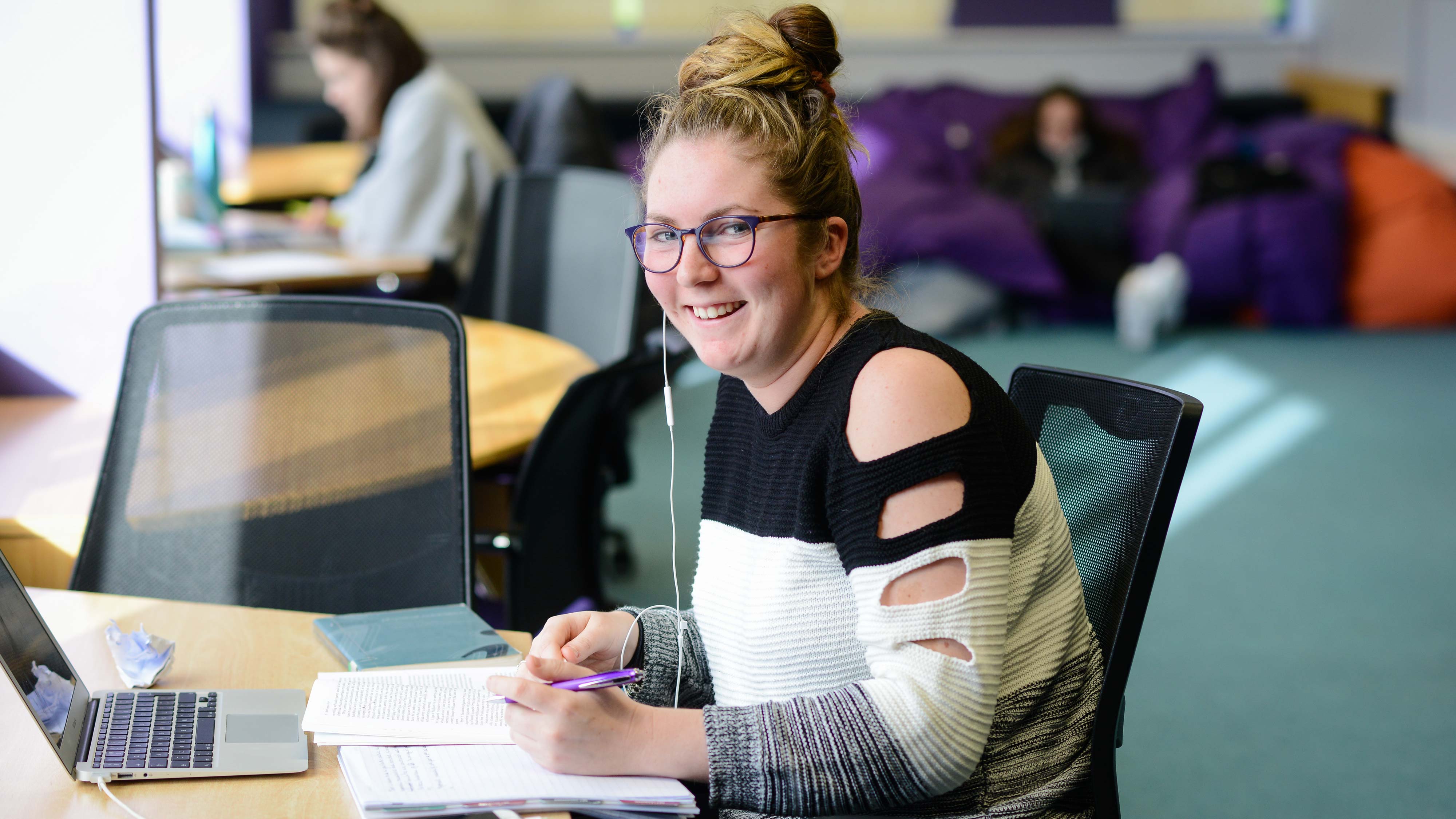 Student smiles at camera in the library