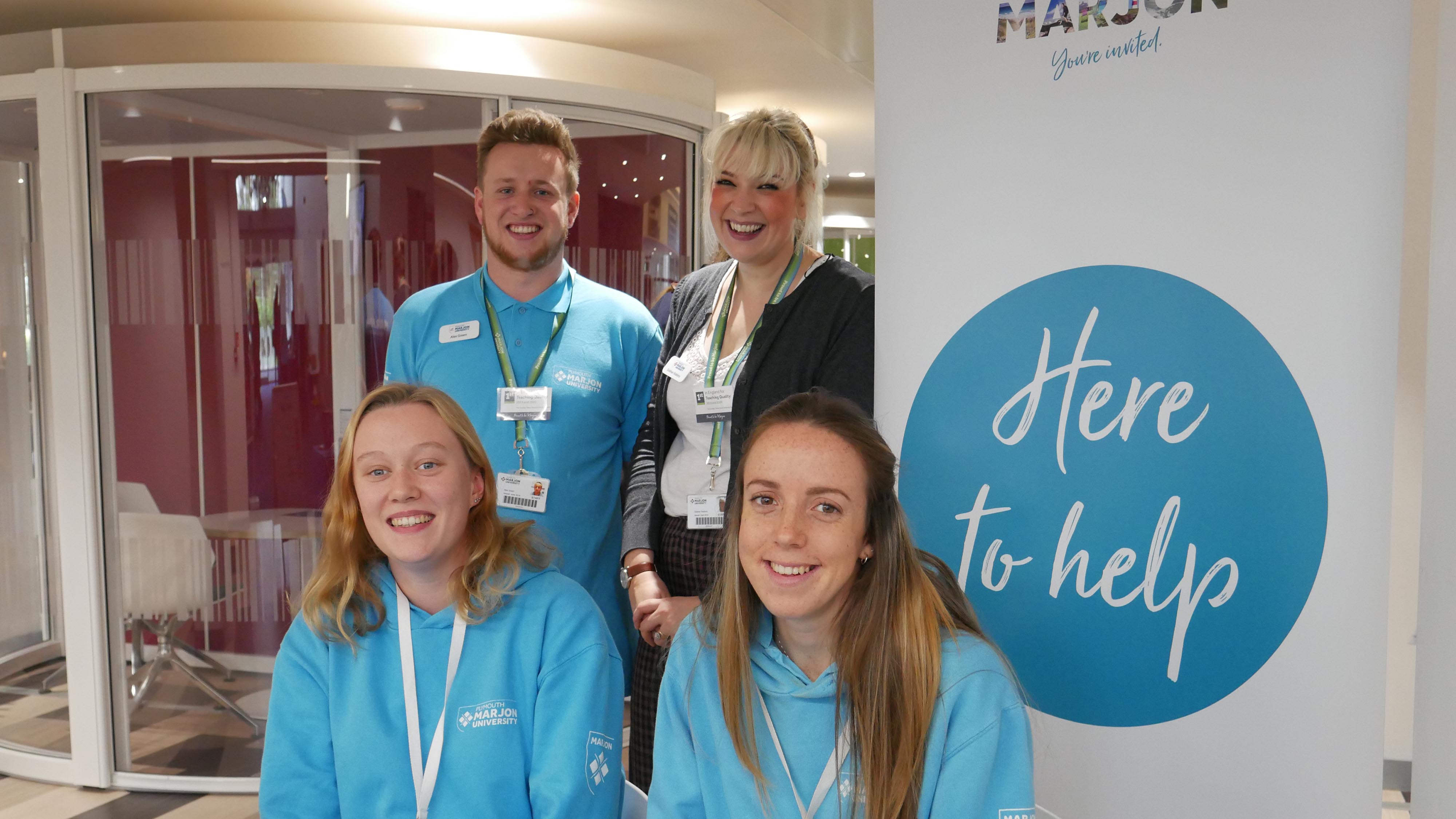 Students and staff next to a 'here on help' sign
